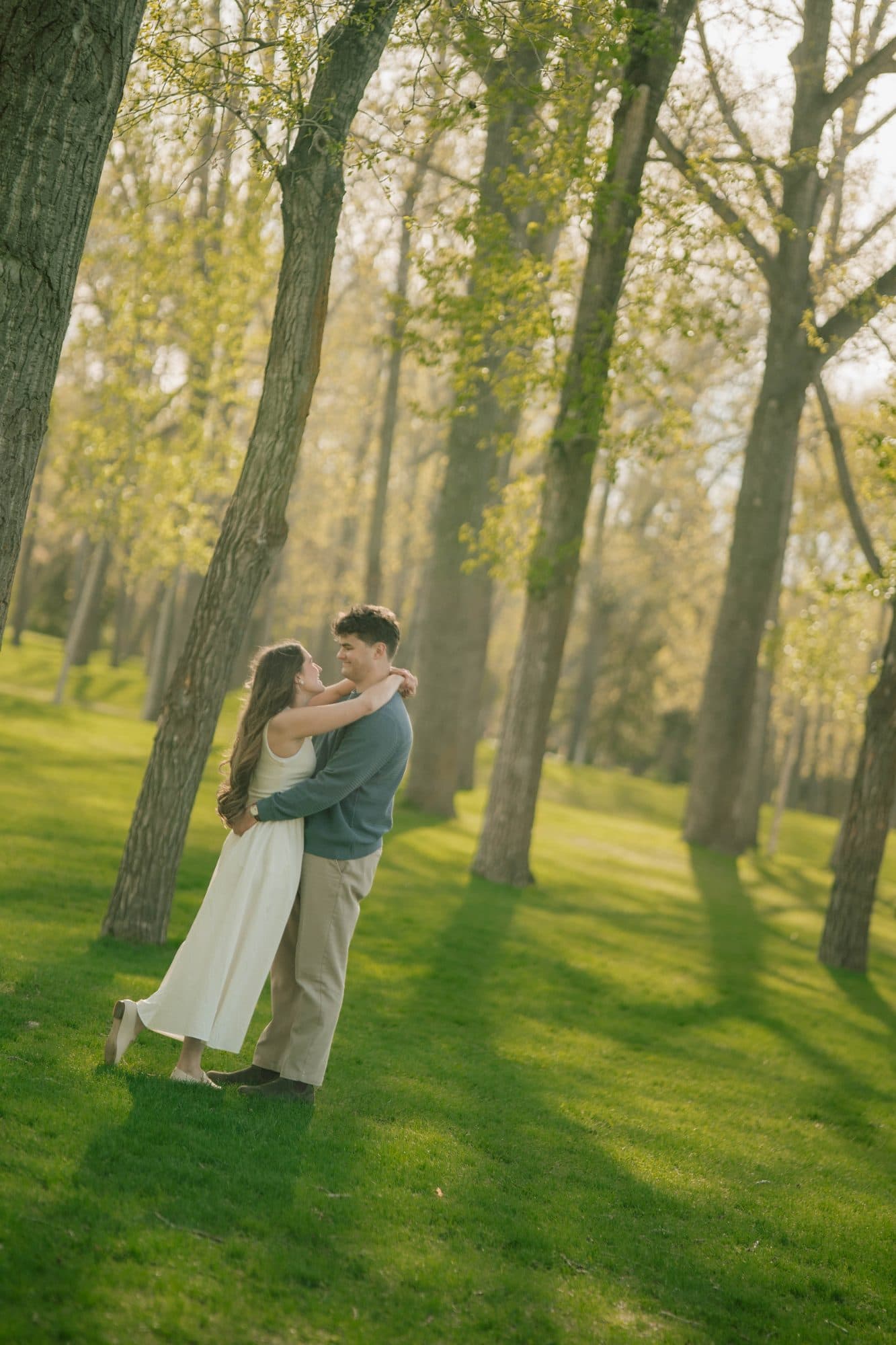 Brooklyn and William embracing beneath tall trees